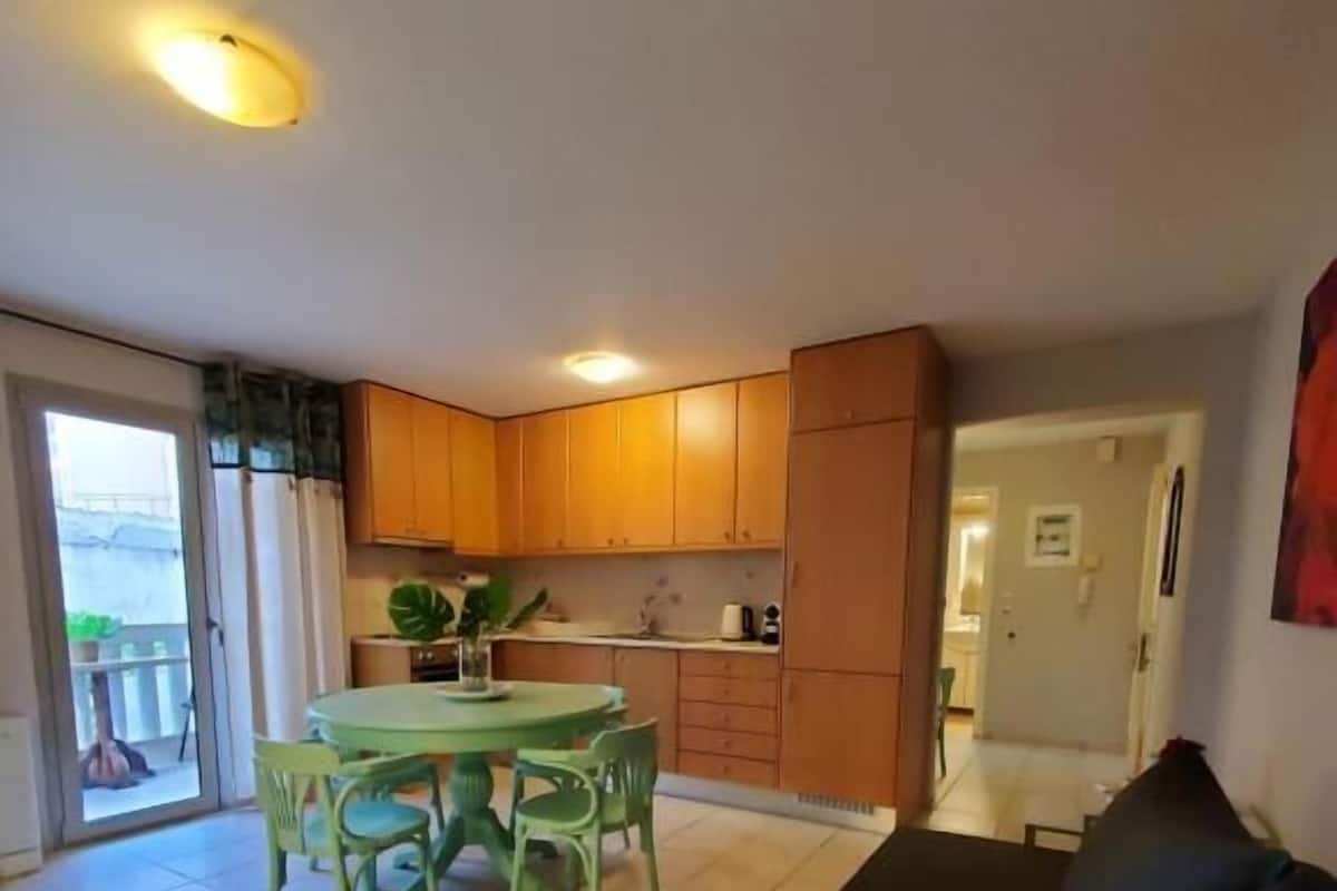 A compact living space with a dining area, kitchenette, and a large sofa.