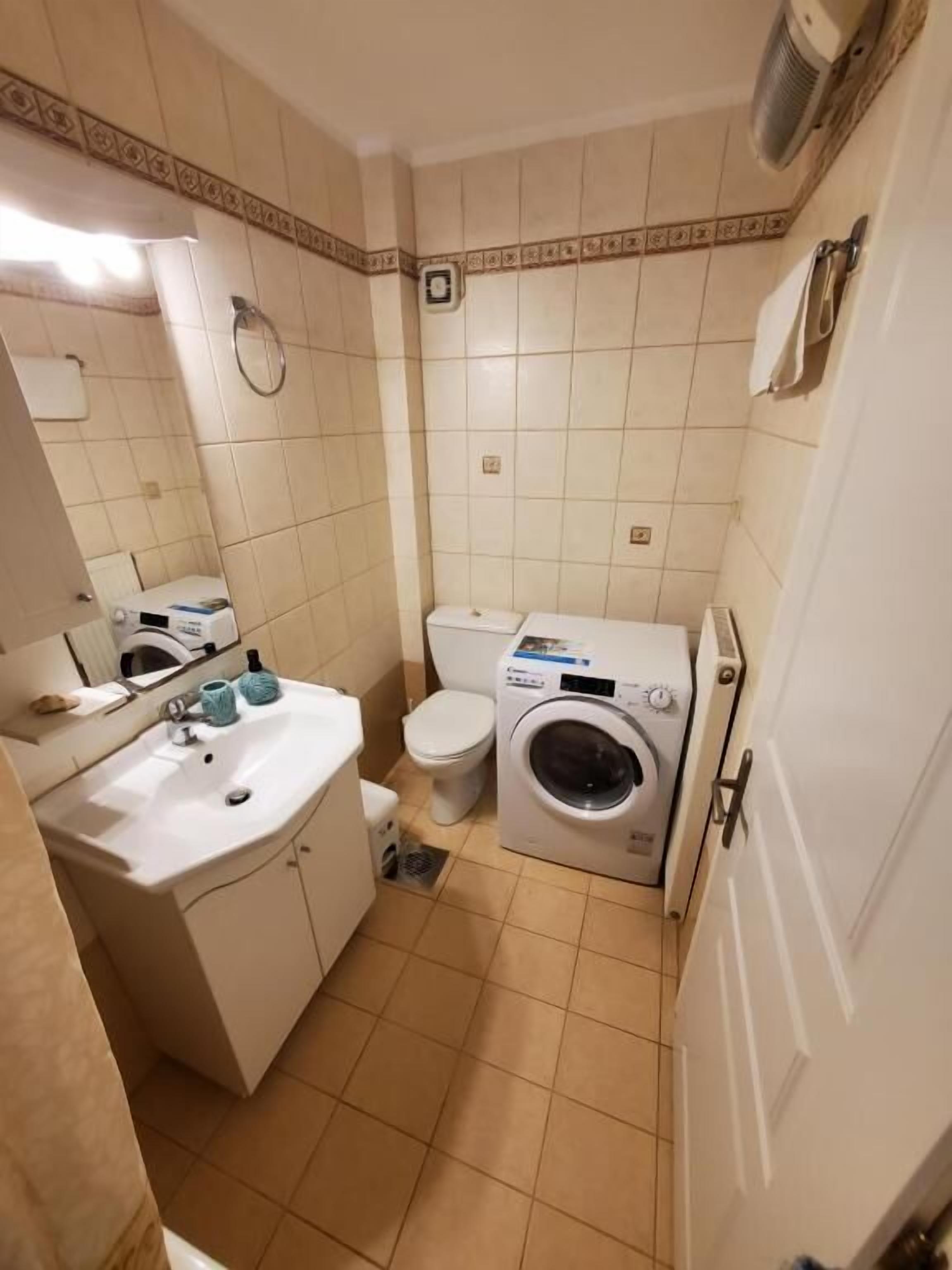 Een kleine badkamer met een wastafel, toilet en wasmachine.