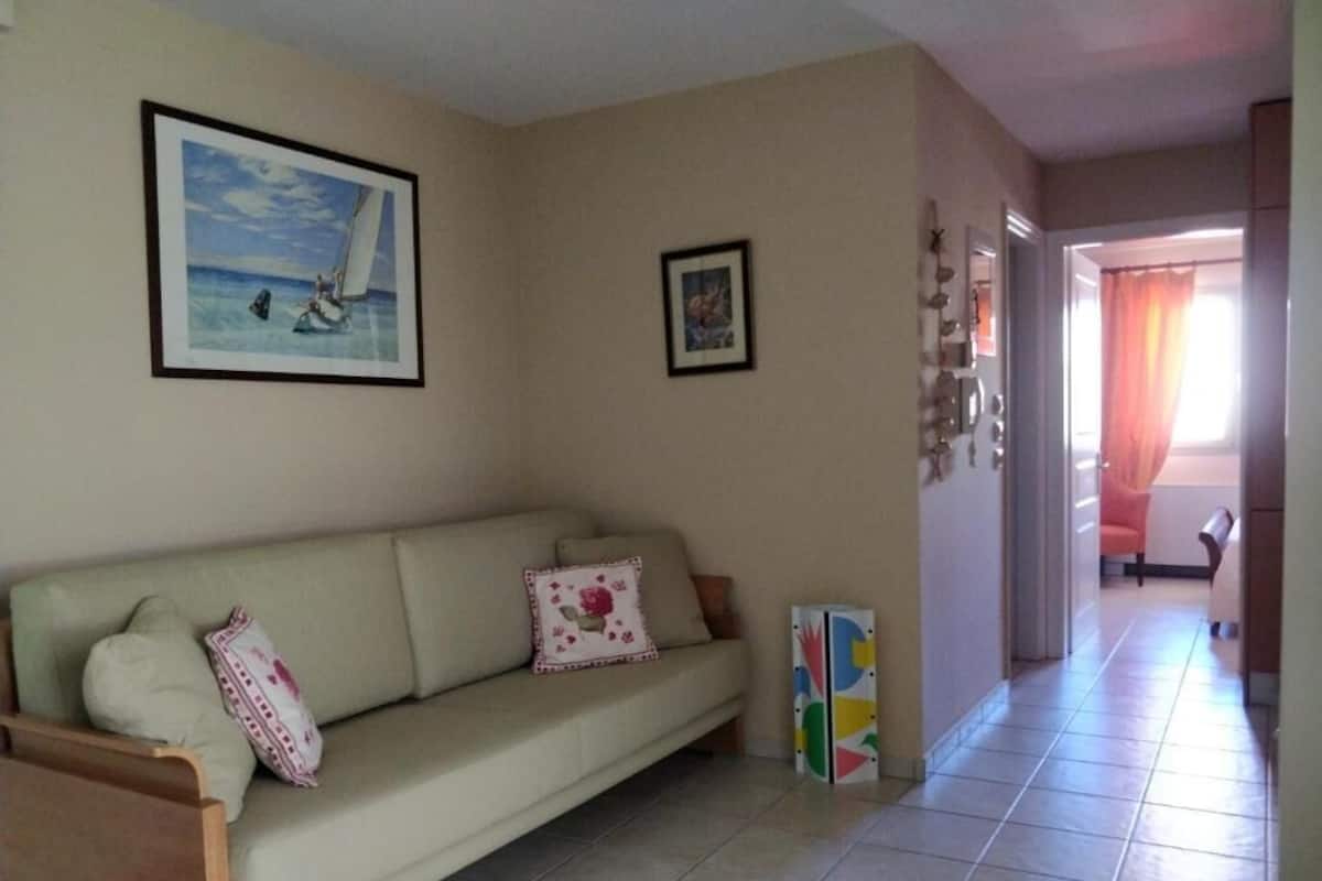 A living room with a beige sofa, a framed picture of a sailboat, and a colorful abstract painting.