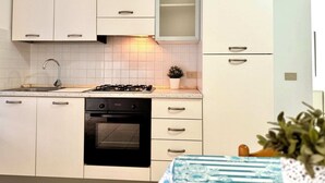 Une cuisine moderne avec des meubles blancs, une cuisinière à gaz, un four et un évier.
