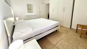 Une chambre à coucher comprenant un lit, une table de chevet, une chaise et une armoire.