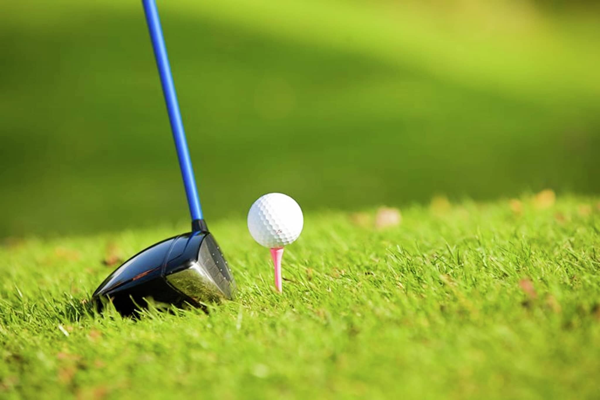 Una pelota de golf sobre un tee en un campo cubierto de hierba.