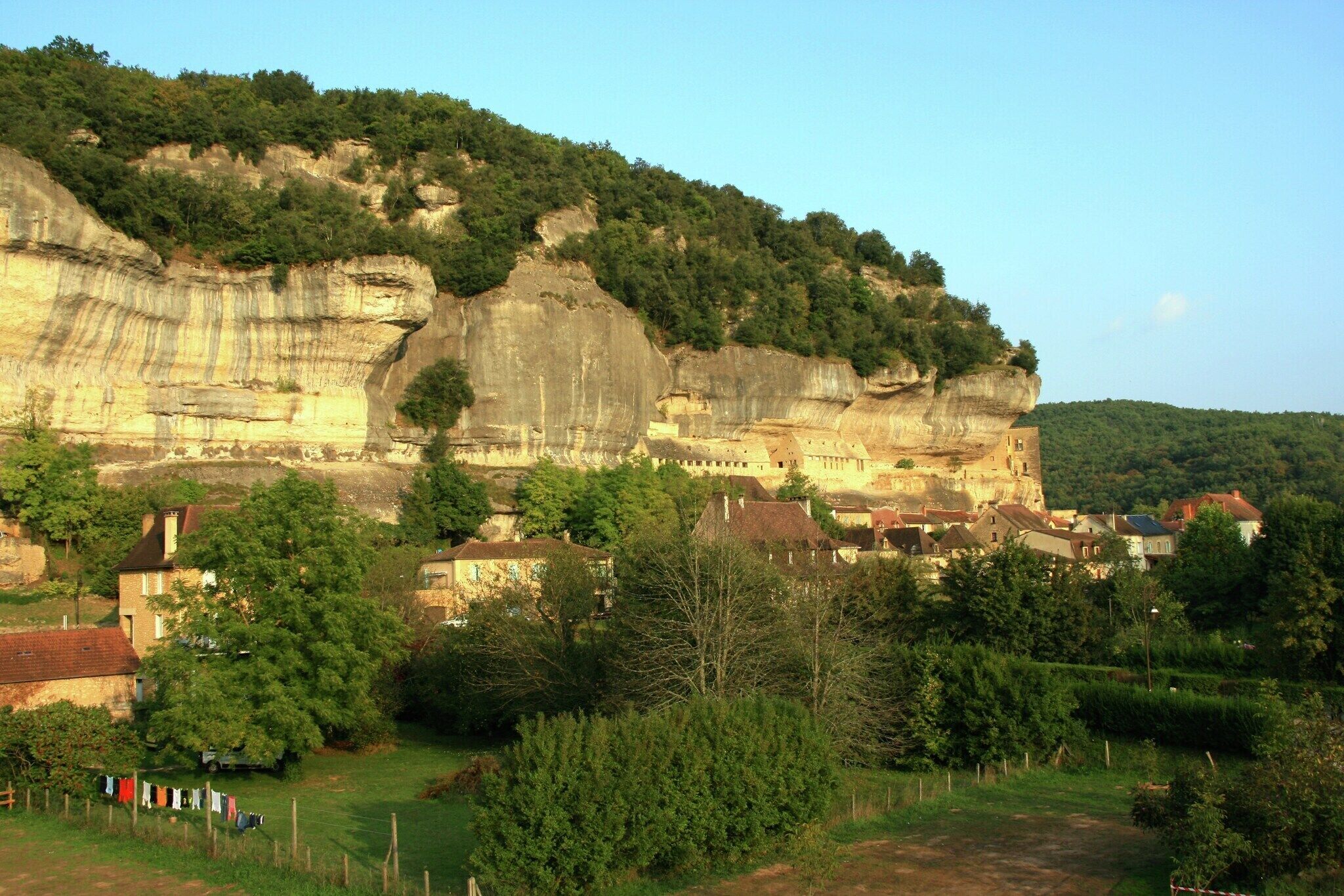 Ein Dorf, eingebettet an einer Klippe, mit Häusern und viel Grün.