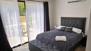 A bedroom with a large bed, a dark headboard, and a sliding glass door leading to an outdoor area.