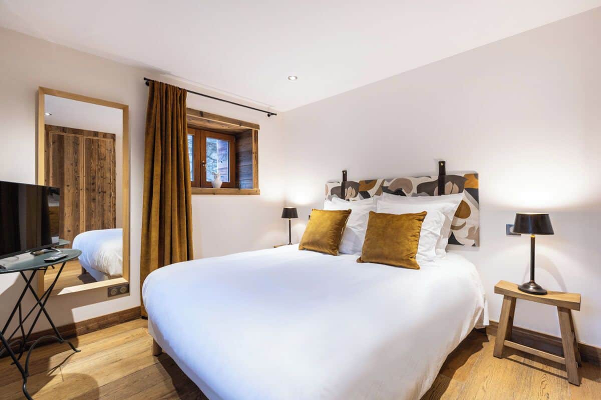 Ein Hotelzimmer mit einem großen Bett, einem Fernseher, einem Schreibtisch und einem fenster mit Vorhängen.