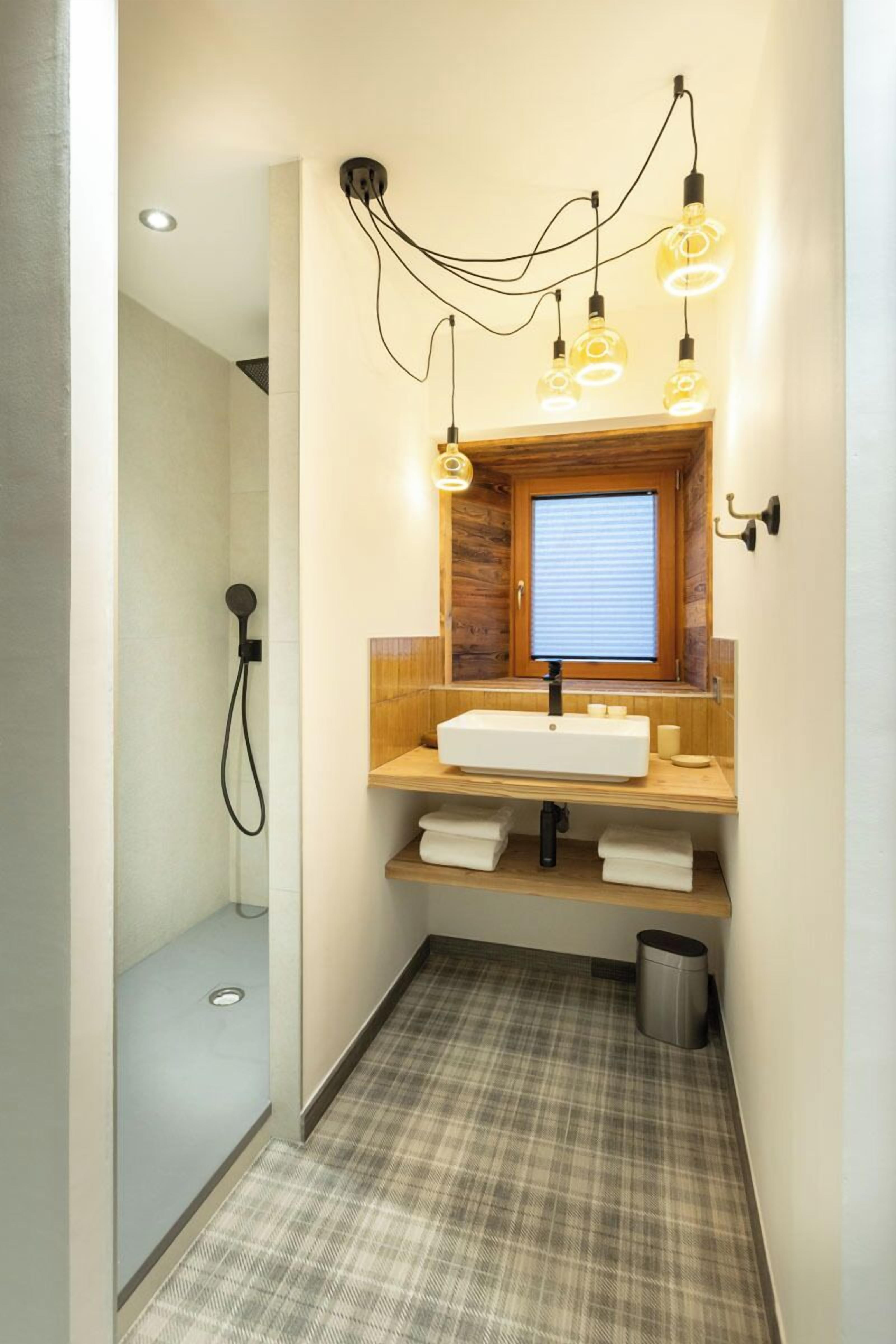Un baño con un mueble de tocador de madera, un lavabo, un espejo y una ducha.