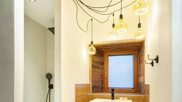 Un baño con un mueble de tocador de madera, un lavabo, un espejo y una ducha.