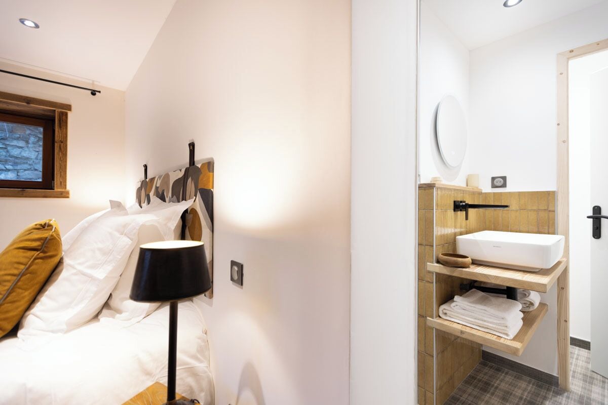 Een slaapkamer met een bed, een bedlamp en een raam.