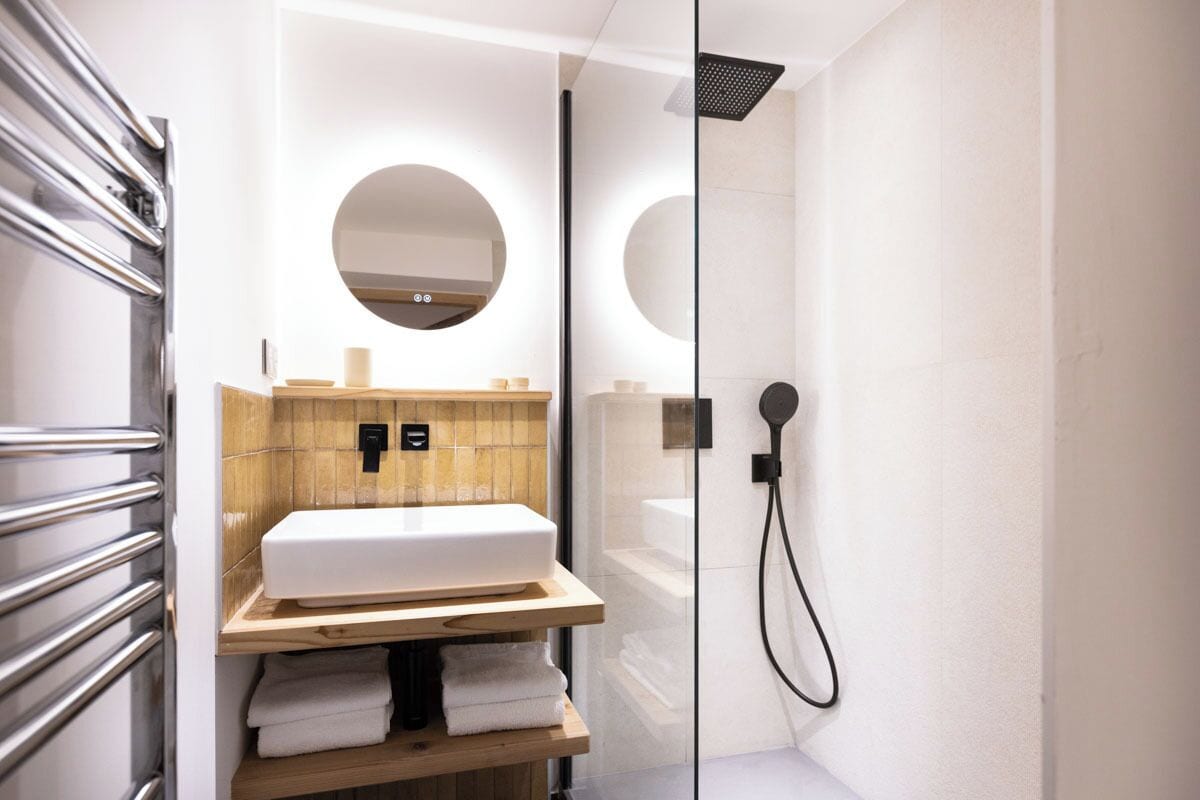 Un baño moderno con cabina de ducha de vidrio, lavamanos blanco y tocador de madera.