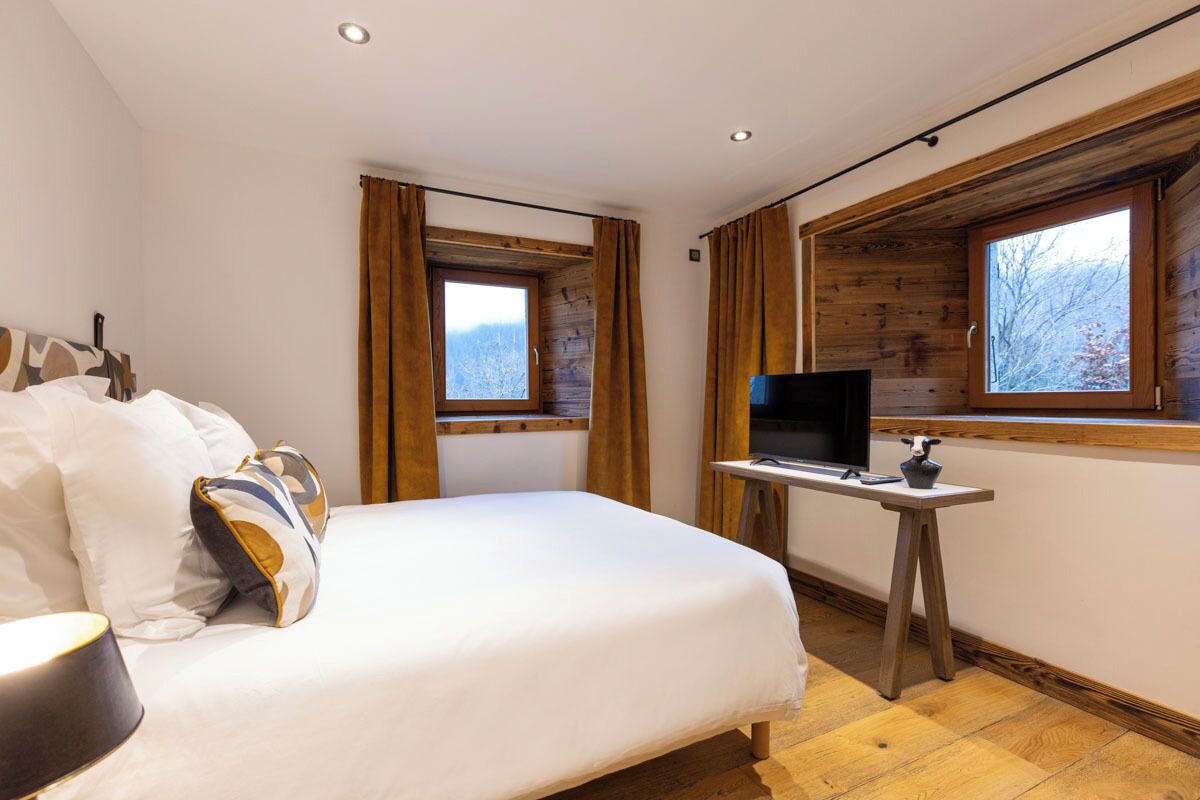 Une chambre à coucher avec un lit, une télévision et une fenêtre avec des rideaux.