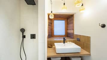 A modern bathroom with a wooden vanity, a built-in window, and a shower area.