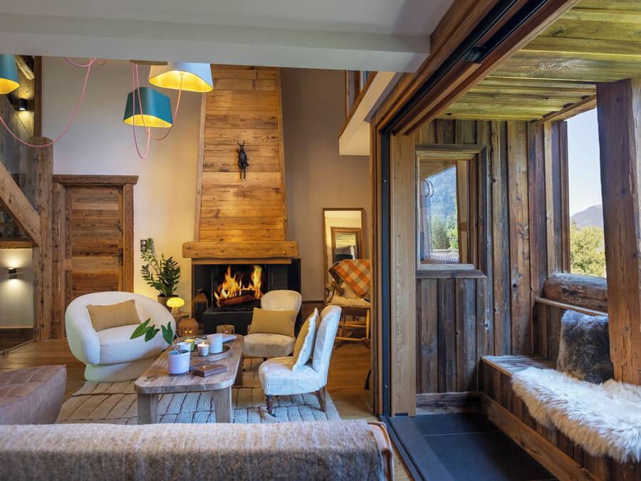 A cozy living room with a fireplace, wooden beams, and comfortable seating.