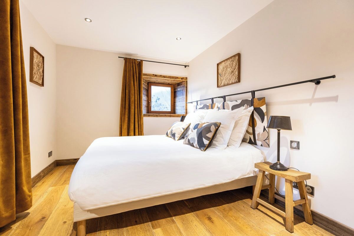 Een slaapkamer met een bed, een raam, een nachtkastje en een lamp.