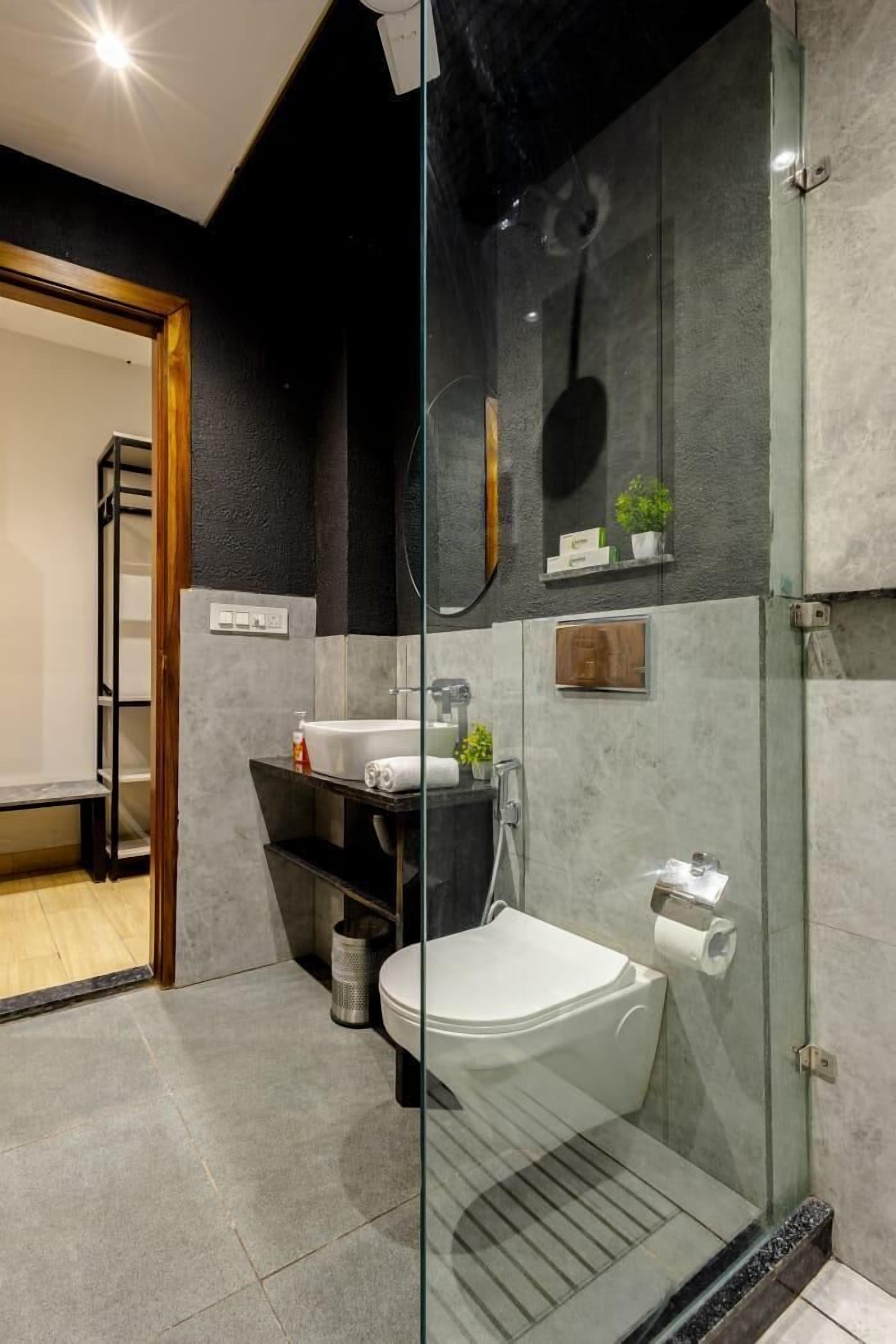 A modern bathroom with a glass shower enclosure, a white toilet, and a sink with a mirror above it.