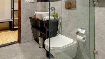 A modern bathroom with a glass shower enclosure, a white toilet, and a sink with a mirror above it.