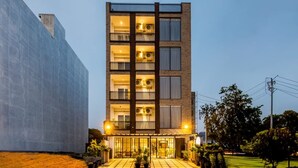 A multi-story hotel with balconies, a well-lit entrance, and a landscaped garden area. - Imperial Stayz (Gurugram)