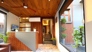 A reception area with a wooden ceiling, a marble floor, and potted plants. - Imperial Stayz (Gurugram)