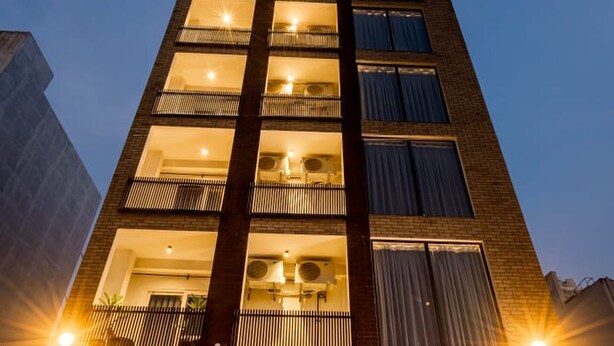 A multi-story building with balconies, large windows, and a well-lit entrance. - Imperial Stayz (Gurugram)