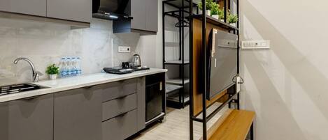 Una cocina moderna con armarios grises, un lavamanos de acero inoxidable y un banco de madera.