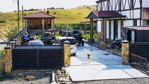 Un parking clos, avec des véhicules, un chien et un bâtiment doté d’un toit à pignon.