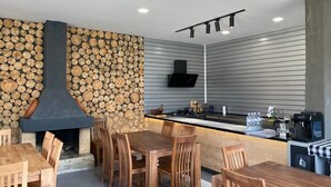 Une cuisine moderne avec une cheminée en pierre, une table à manger en bois et des chaises.