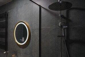 Ein modernes Badezimmer mit rundem Spiegel, Duschbrause und Handtuchhalter.