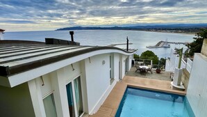 A rooftop pool with a view of the sea and a dock.