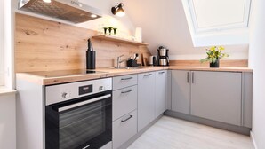 Une cuisine moderne dotée d’un four Bosch, de meubles gris, d’un plan de travail en bois et d’une fenêtre offrant une belle vue.