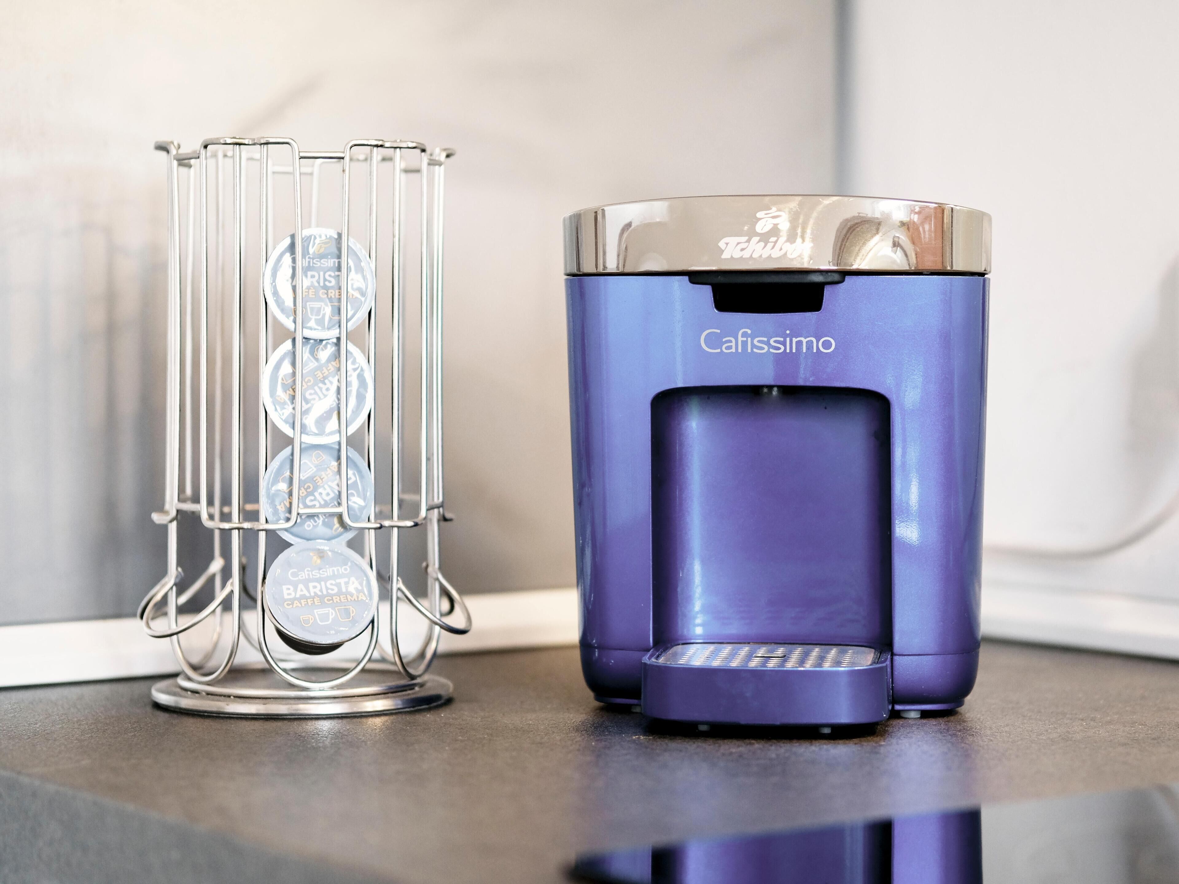A coffee machine and a coffee cup holder with multiple cups on a countertop.