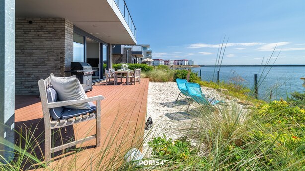 A modern outdoor deck with a grill, seating, and a view of the sea. - Dock 76 Main - First Row, Large Terrace, Sea View, Close to the Beach, EV Chargi (Olpenitz)