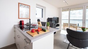 A modern kitchen with a large island, a dining area with a view, and a balcony with a table and chairs. - Dock 76 Main - First Row, Large Terrace, Sea View, Close to the Beach, EV Chargi (Olpenitz)