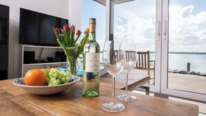 A table with a bottle of wine, two glasses, a bowl of fruit, and tulips. - Dock 76 Main - First Row, Large Terrace, Sea View, Close to the Beach, EV Chargi (Olpenitz)