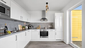 Een moderne keuken met witte kastjes, een Bosch oven, een koffiezetapparaat en een hangende lamp.