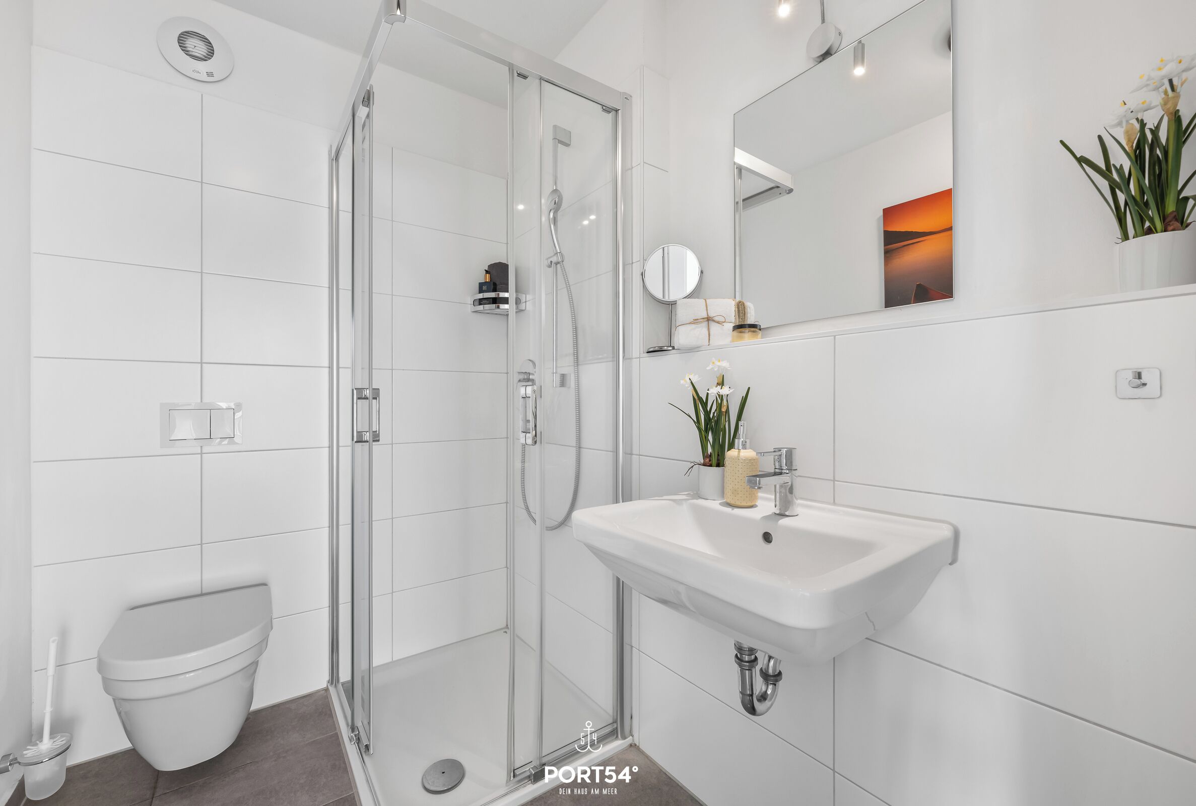 Ein modernes Badezimmer mit einer Duschkabine, einem weißen Waschbecken und einer Toilette.