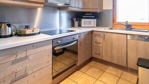 Een keuken met houten kastjes, een magnetron, een waterkoker en een spoelbak.