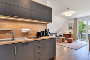 Una cocina moderna con horno empotrado, pileta y cafetera.