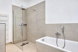 Une salle de bain moderne avec une douche à parois de verre, une baignoire blanche et un porte-serviettes.