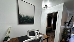 Ein moderner Arbeitsraum mit Schreibtisch, Stuhl und einem gerahmten Bild von einem Wald.