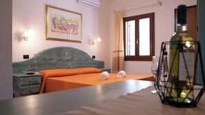 A hotel room with a bed, a nightstand, a lamp, and a painting on the wall. - Violet Residence In Orosei (Orosei)
