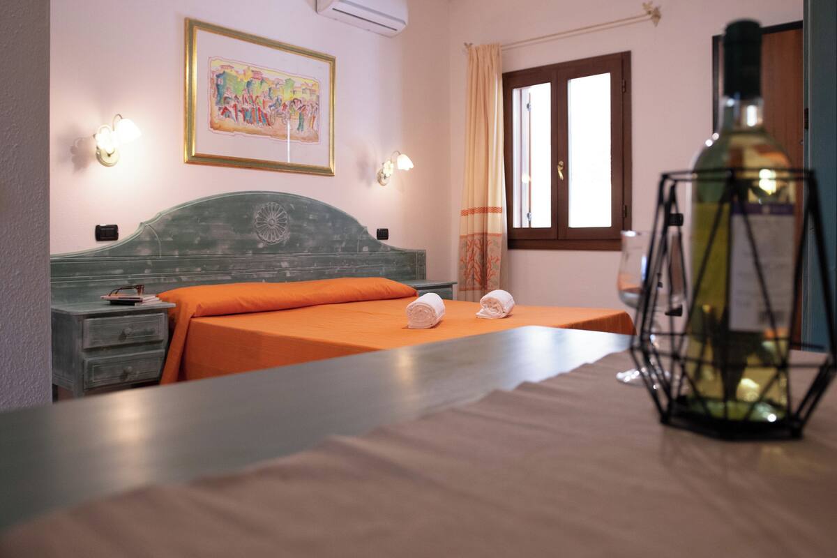 Una camera d'albergo con un letto, un comodino, una lampada e un quadro appeso al muro.
