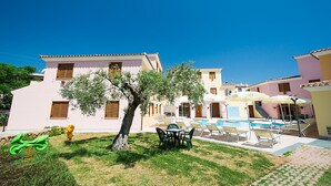 A sunny courtyard with a swimming pool, lounge chairs, and a small tree. - Violet Residence In Orosei (Orosei)