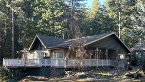 Een chalet met een overdekte veranda, een omheind terras en een stenen fundering.