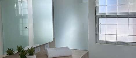 A modern bathroom with a large mirror, a toilet, and a window.