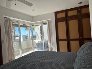 Een slaapkamer met een bed, een schuifdeur naar een balkon en een houten garderobe.