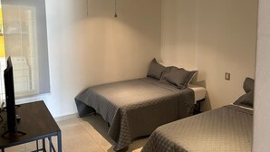 Ein Schlafzimmer mit Bett, Schreibtisch, Stuhl, Deckenventilator und Fenster.