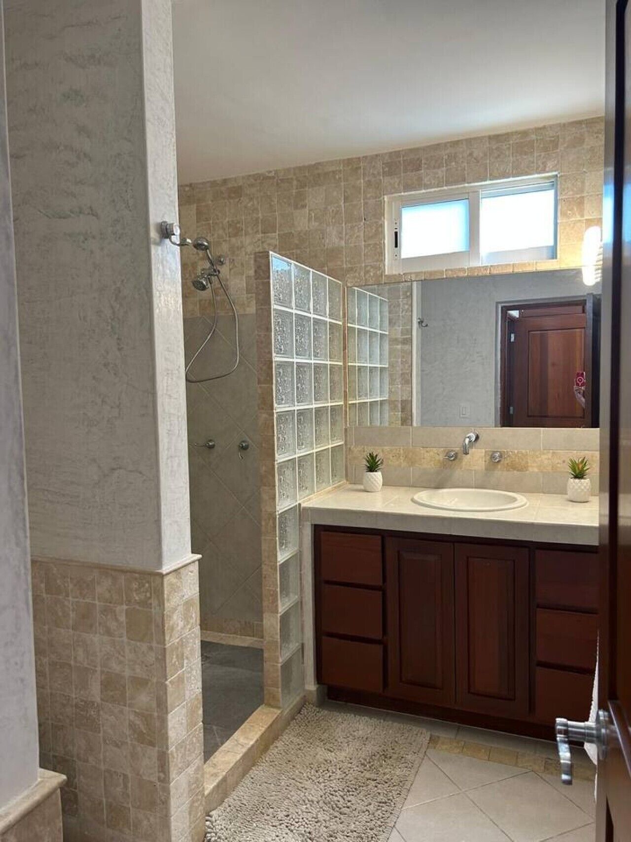 Een badkamer met een douche, een wastafel en een spiegel.