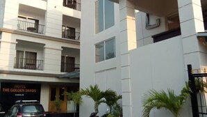 A hotel with a sign reading "The Golden Sands Hotel". There are multiple balconies with railings, and a few potted plants in front of the building. - HOTEL THE GOLDEN SANDS (Calangute)