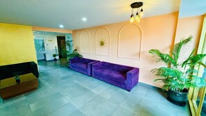 A reception area with a purple sofa, a wooden bench, and potted plants. - HOTEL THE GOLDEN SANDS (Calangute)