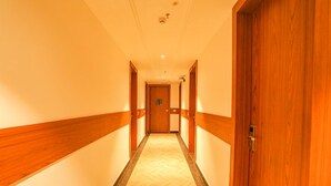 A hotel hallway with wooden paneling on the walls and a herringbone-patterned floor. - Hotel Swarn Bhoomi (Kanpur)
