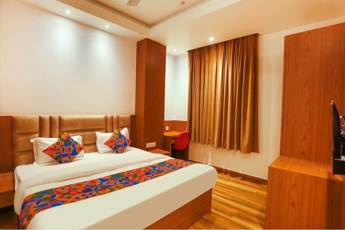 A hotel room with a large bed, wooden headboard, a desk, and a chair.